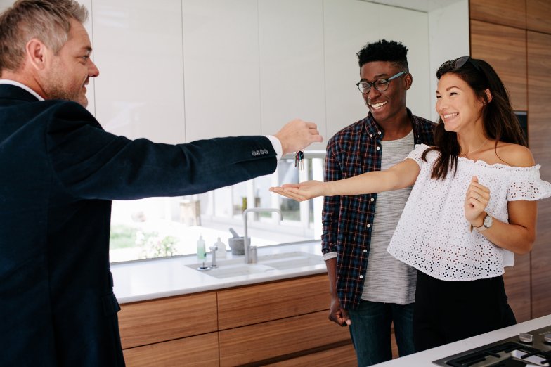 Real estate agent handing house keys to new home buyers